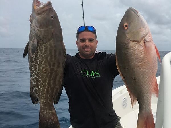 Man holds up fish caught on his trip in two hands